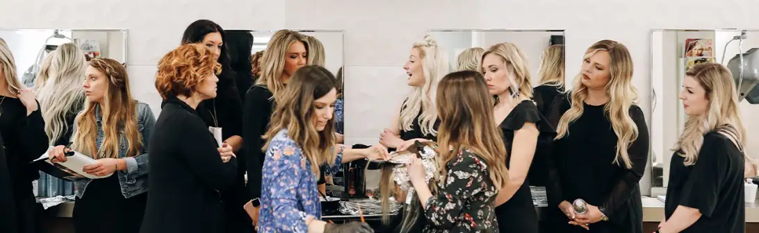 A group of stylists working and interacting in a busy hair salon, reflecting a collaborative and professional environment